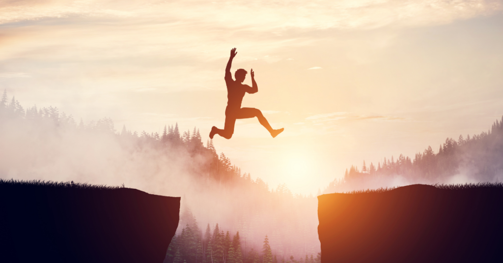 man jumping from one cliff to another